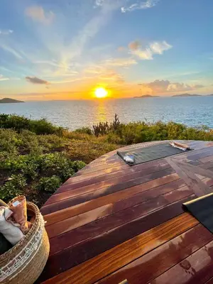 a wooden deck with a sunset over the ocean at The Aerial, BVI in Tortola Island
