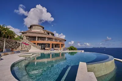 a swimming pool in front of a building next to the ocean at The Aerial, BVI in Tortola Island