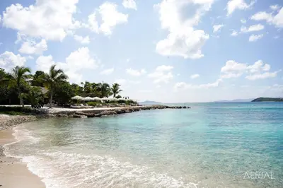 a beach with a group of umbrellas and the ocean at The Aerial, BVI in Tortola Island