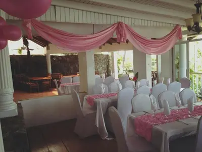 a room with white chairs and tables and pink curtains at Fort Burt Hotel in Road Town
