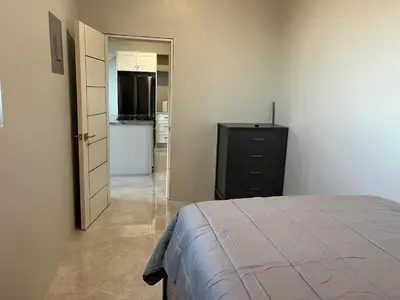 a bedroom with a bed and a dresser and a kitchen at Exquisitely Threadfall in Cane Garden Bay