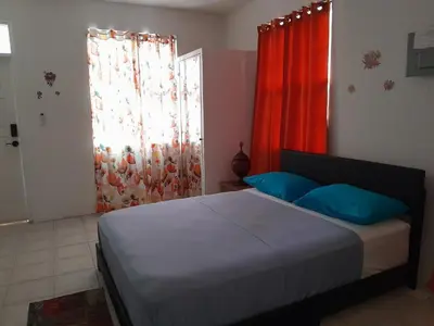 a bedroom with a bed with blue pillows and a window at Abigail Diamond 1 Bedroom near Nanny Cay Marina in Tortola Island