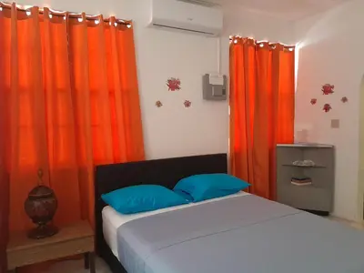 a bedroom with orange curtains and a bed with blue pillows at Abigail Diamond 1 Bedroom near Nanny Cay Marina in Tortola Island