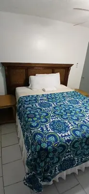 a bed with a blue and white quilt on it at Beach Front Haven, by More Than Beauty Properties in Tortola Island