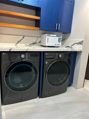 a washer and dryer in a kitchen with blue cabinets at Zafira Luxe in Leonards