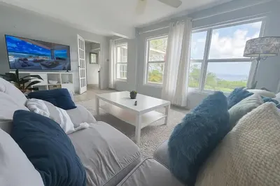 a living room with a couch with blue pillows at BluEdge Villa VIP Resort Access in Tortola Island