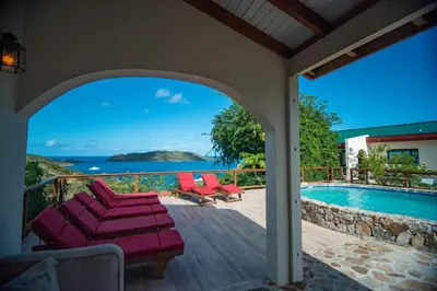 a patio with a view of the ocean and a swimming pool at Tamarind Villa in Virgin Gorda
