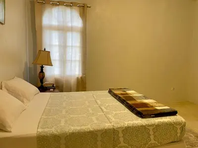 a bed in a bedroom with a window and a lamp at Abigail's Esmeralda 2 bedrom Apt in Tortola Island
