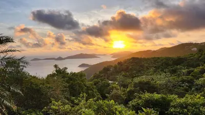 a sunset over the ocean with forests and mountains at SUNFLOWER LANE QUEEN Balcony Room APARTMENT in Tortola Island