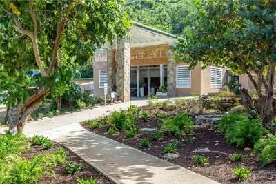 a garden in front of a building with trees at Wyndham Tortola BVI Lambert Beach Resort in East End