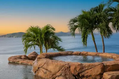 a rock pool with palm trees in the water at Peter Island Resort in Anderson