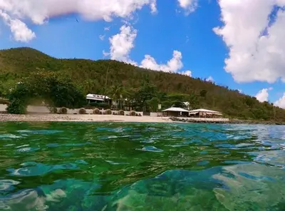 a body of water with a beach and a mountain at Sugar Mill Hotel in Great Carrot Bay