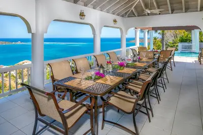 a dining room with a table and chairs and the ocean at TAMAR VILLA in Virgin Gorda