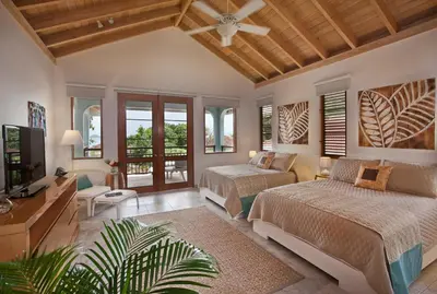 a bedroom with two beds and a flat screen tv at BLUE LAGOON in Virgin Gorda