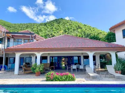 a house with a patio and a swimming pool at CARIBBEAN WIND in Virgin Gorda