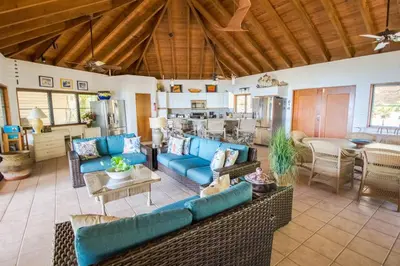 a living room with blue couches and a kitchen at LOBLOLLY in Virgin Gorda