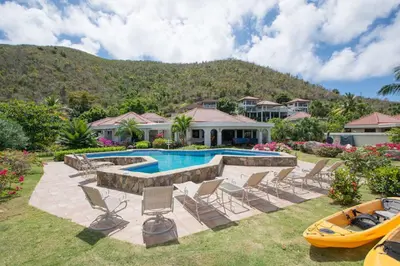 a backyard with a pool and chairs and a house at SANDCASTLE in Virgin Gorda