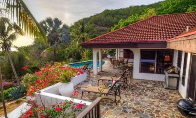 a house with a patio with chairs and flowers at VILLA VALMARC in Virgin Gorda