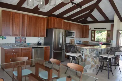 a kitchen with wooden cabinets and a bar with chairs at SERENDIPITY in Virgin Gorda