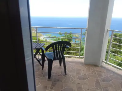 a table and chair on a balcony with the ocean at Abigail's Splendor -2 Bedroom Entire Apartment in Tortola Island