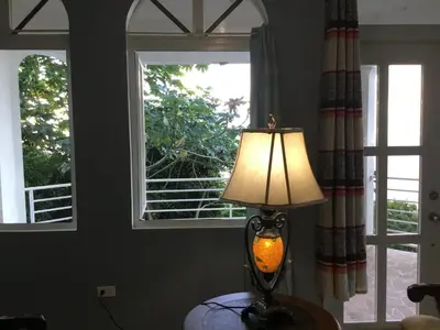 a lamp sitting on a table in front of two windows at Abigail's Splendor -2 Bedroom Entire Apartment in Tortola Island